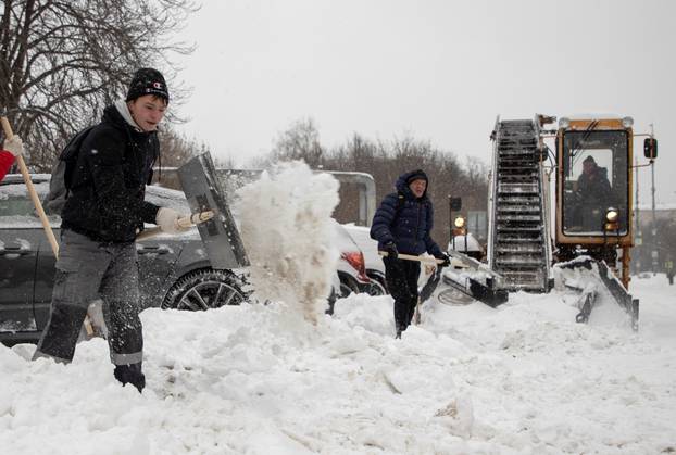Workers remove snow in a street in Moscow