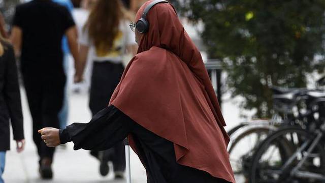 A Muslim woman wearing an abaya walks in a street in Nantes