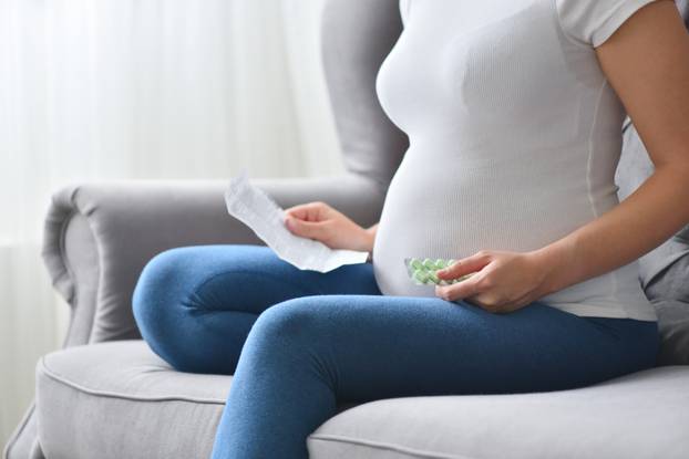 Pregnant woman reads instructions and holds pills