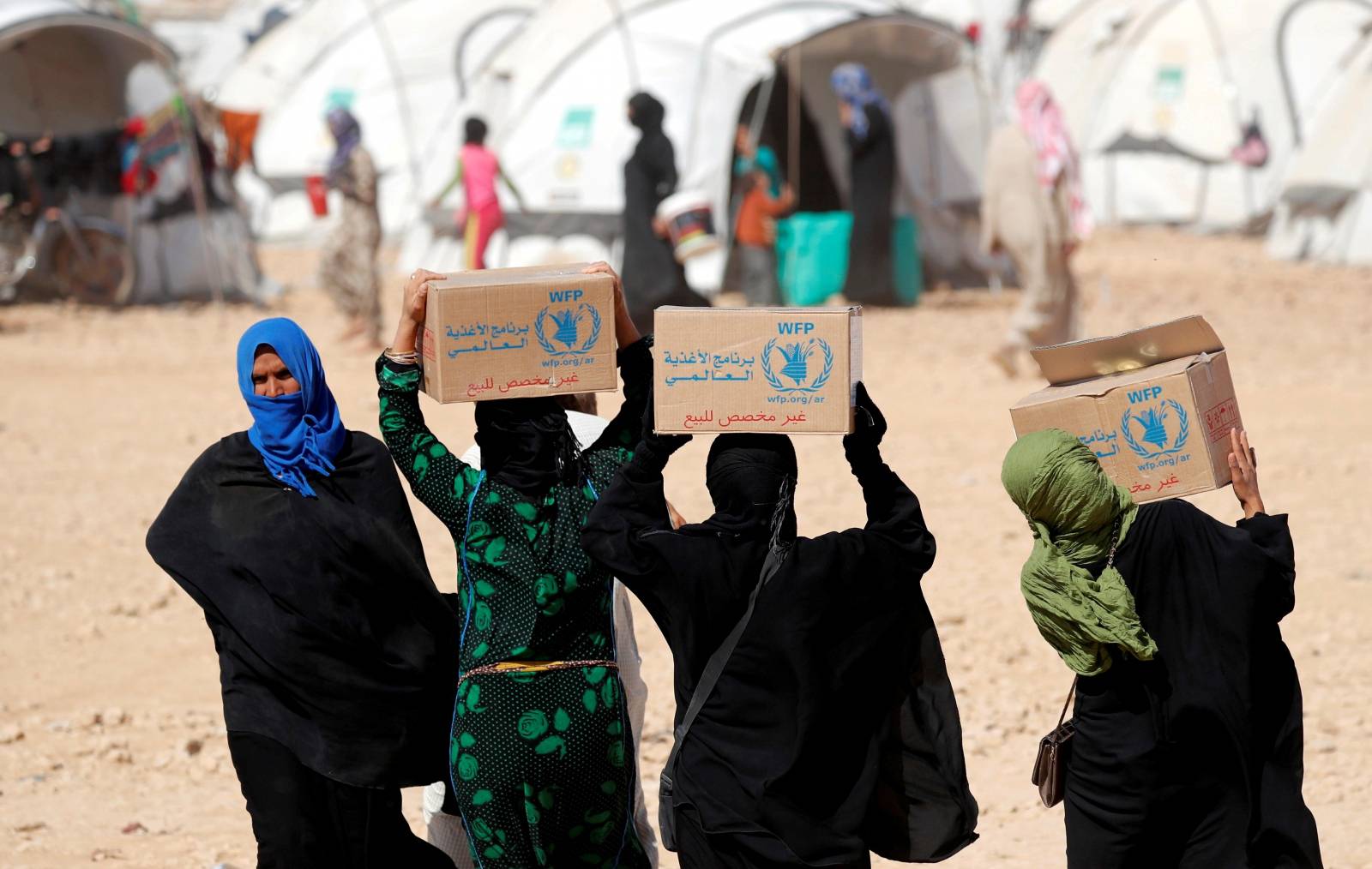 FILE PHOTO: People displaced from fightings between the Syrian Democratic Forces and Islamic State militants carry boxes of food aid given by UN's World Food Programme at a refugee camp in Ain Issa