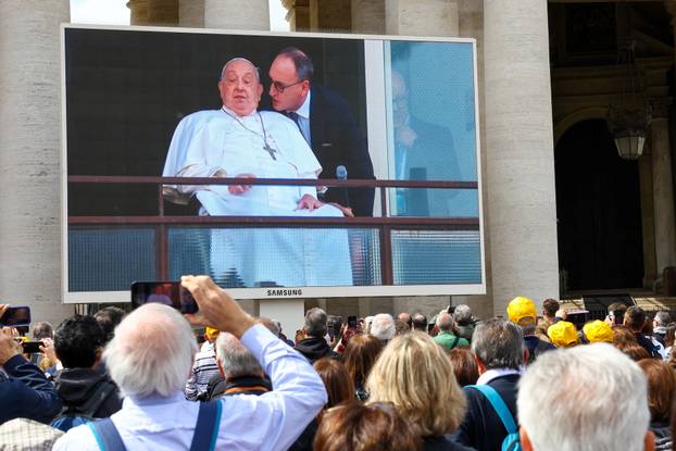 People watch Pope Francis makes first public appearance in five weeks, on a big screen in St. Peter's Square at the Vatican
