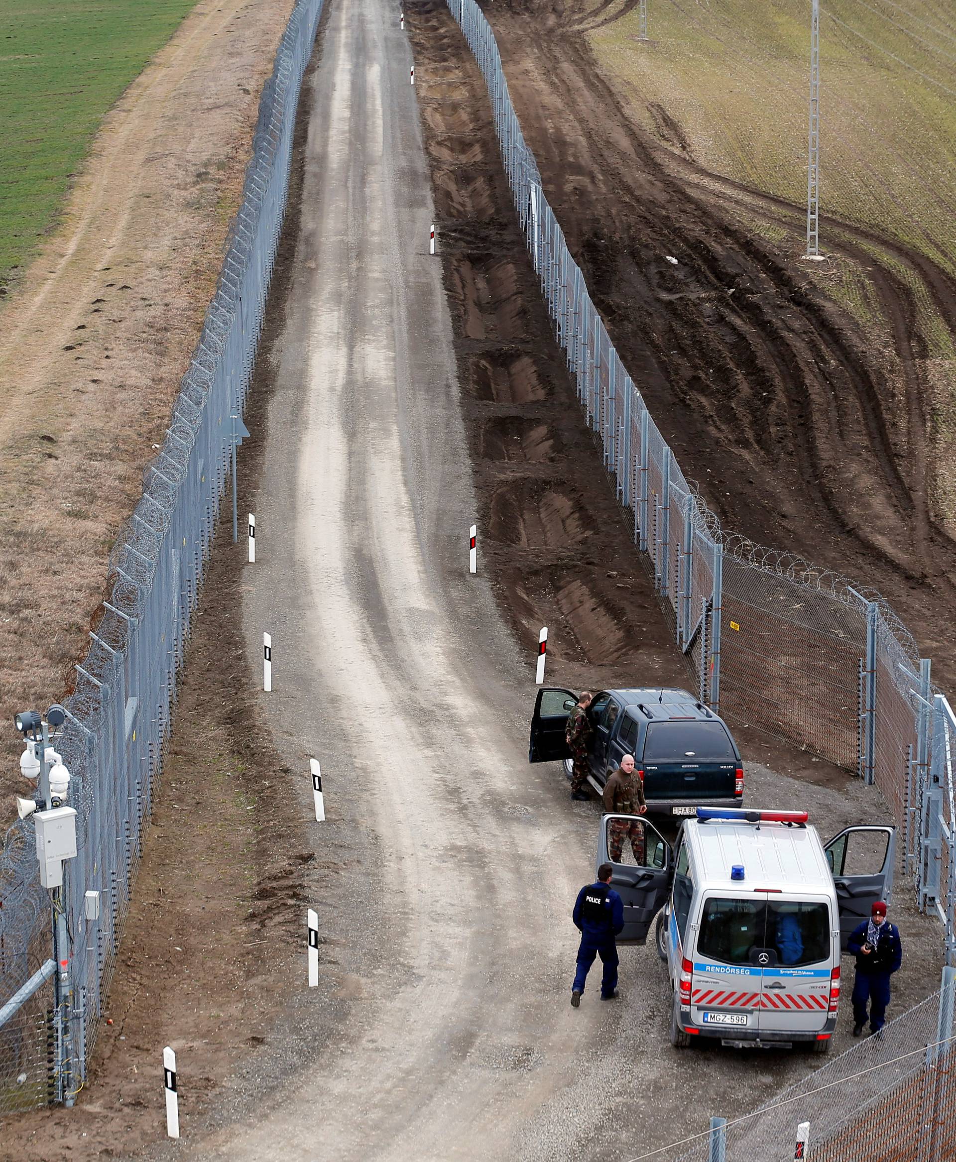 A Hungarian police and soldiers patrol the Hungary-Serbia border, which was recently fortified by a second fence, near the village of Gara