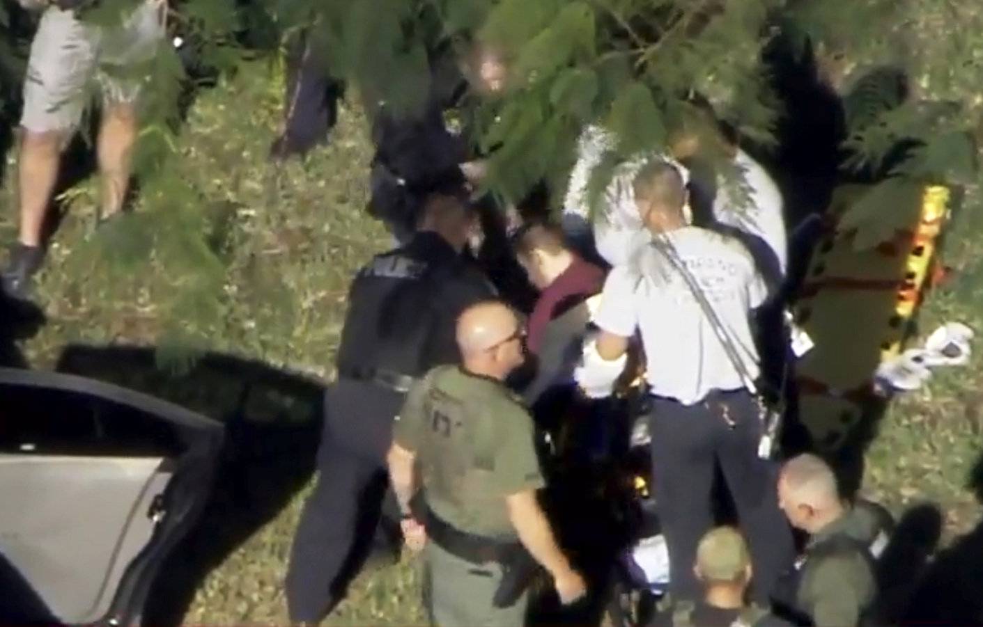 A man placed in handcuffs by police is loaded onto a stretcher near Marjory Stoneman Douglas High School following a shooting incident in Parkland