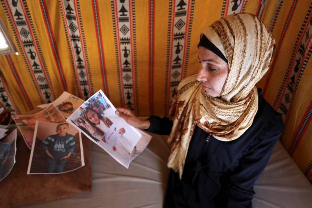 Displaced Palestinian woman Amal Bakron holds a picture of her daughter Olina, who was killed in an Israeli strike, according to the family, at her tent in Gaza City