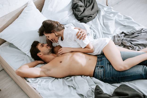 top view of happy girl lying with handsome man on bed