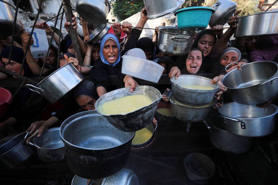 Palestinians wait to receive food from a charity kitchen, amid a hunger crisis, in Gaza City