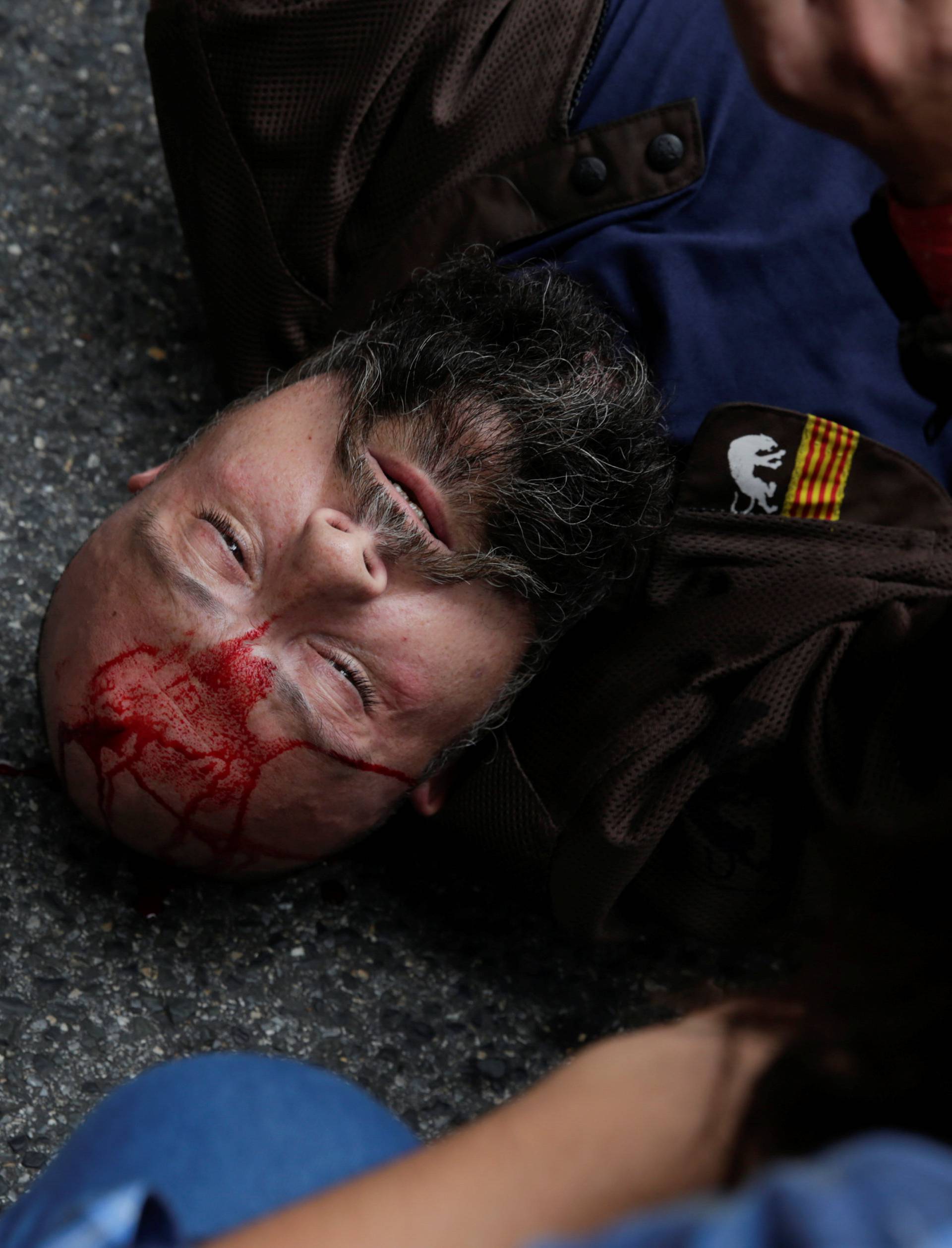 A man injured during clashes with Spanish police lies on the pavement outside a polling station for the banned independence referendum in Tarragona