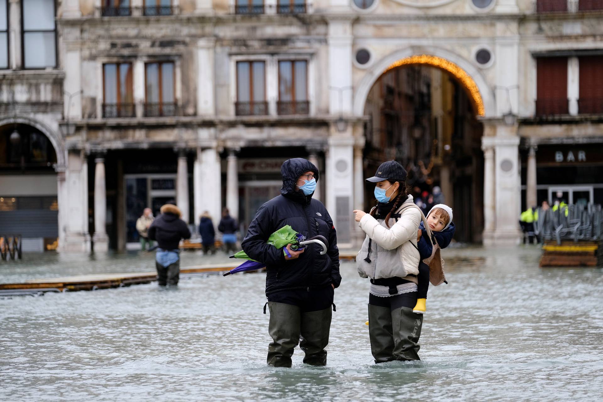 People walk in flooded St. Mark's Square during high tide as the flood barriers known as Mose are not raised, in Venice