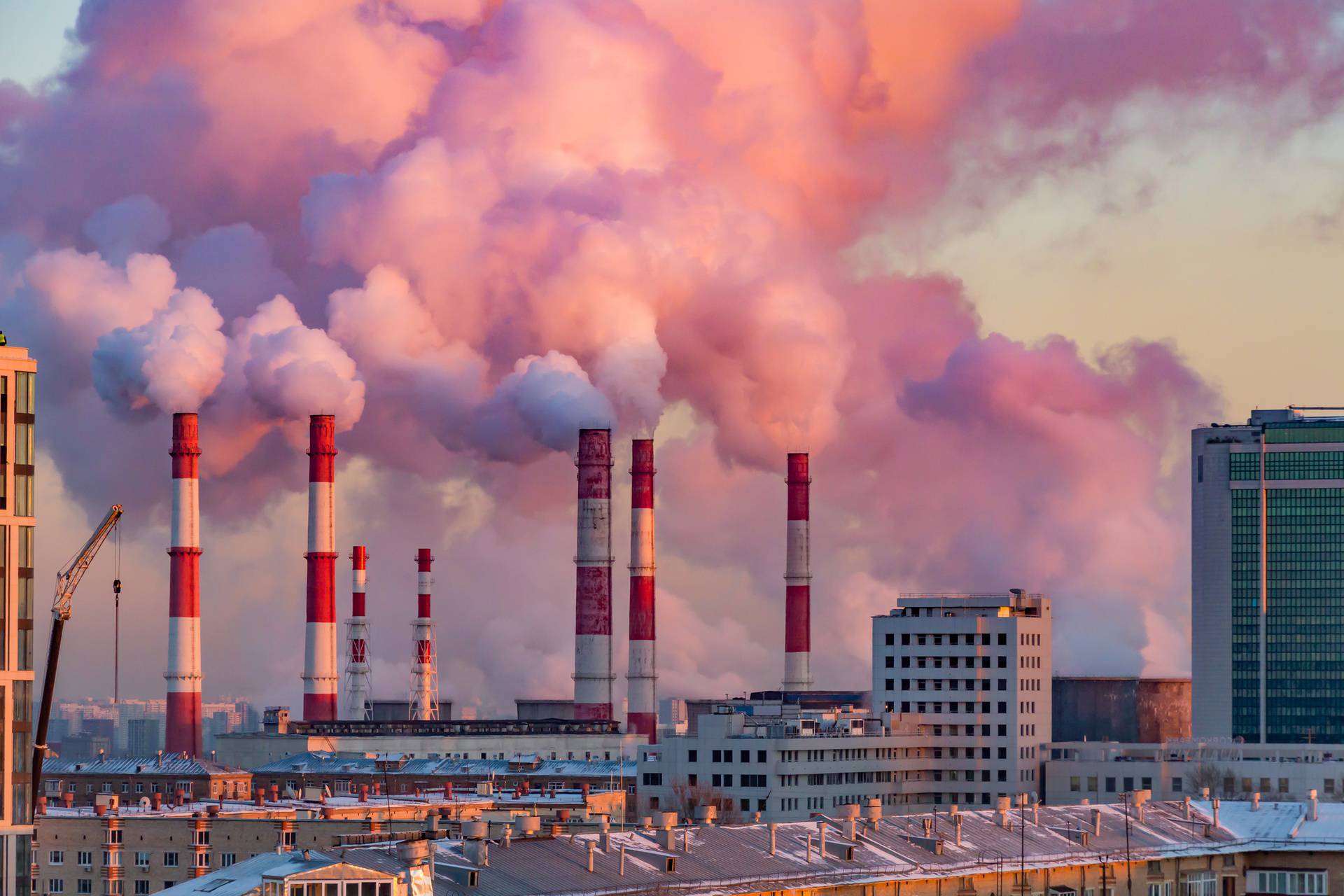 Steam or smoke comes from the pipes. Combined heat and power plant in the city. Landscape at sunset or dawn