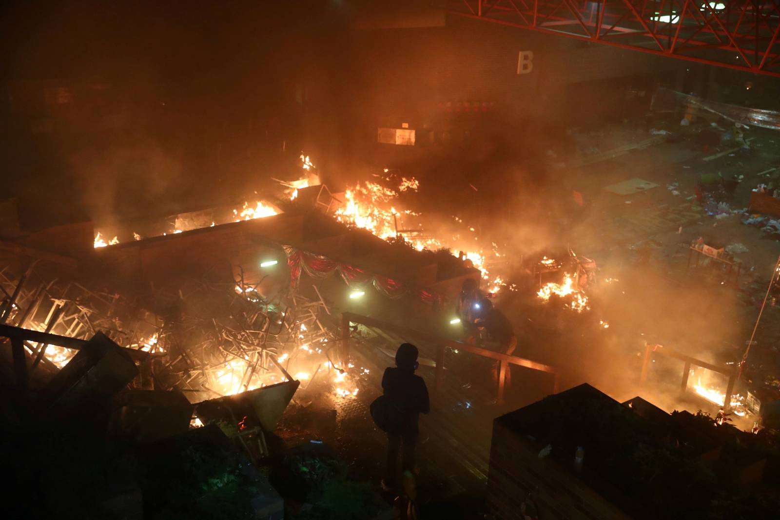 A protester looks at fire at Hong Kong Polytechnic University (PolyU) during an anti-government protest in Hong Kong