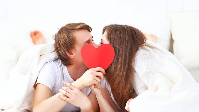 lover couple kissing with a red heart in bed