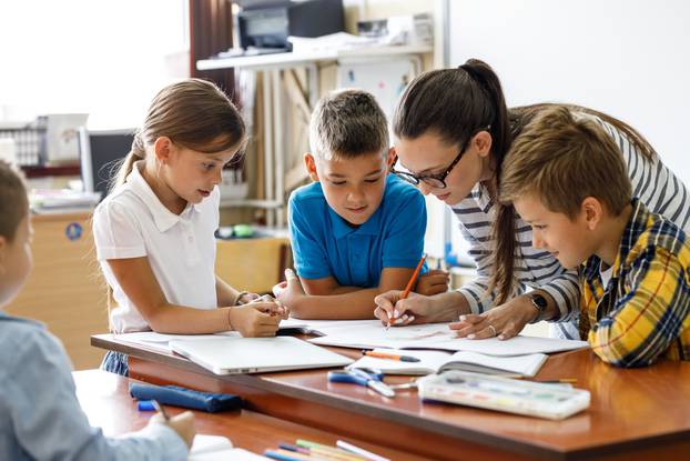 Female,Teacher,Helps,School,Kids,To,Finish,They,Lesson.they,Sitting