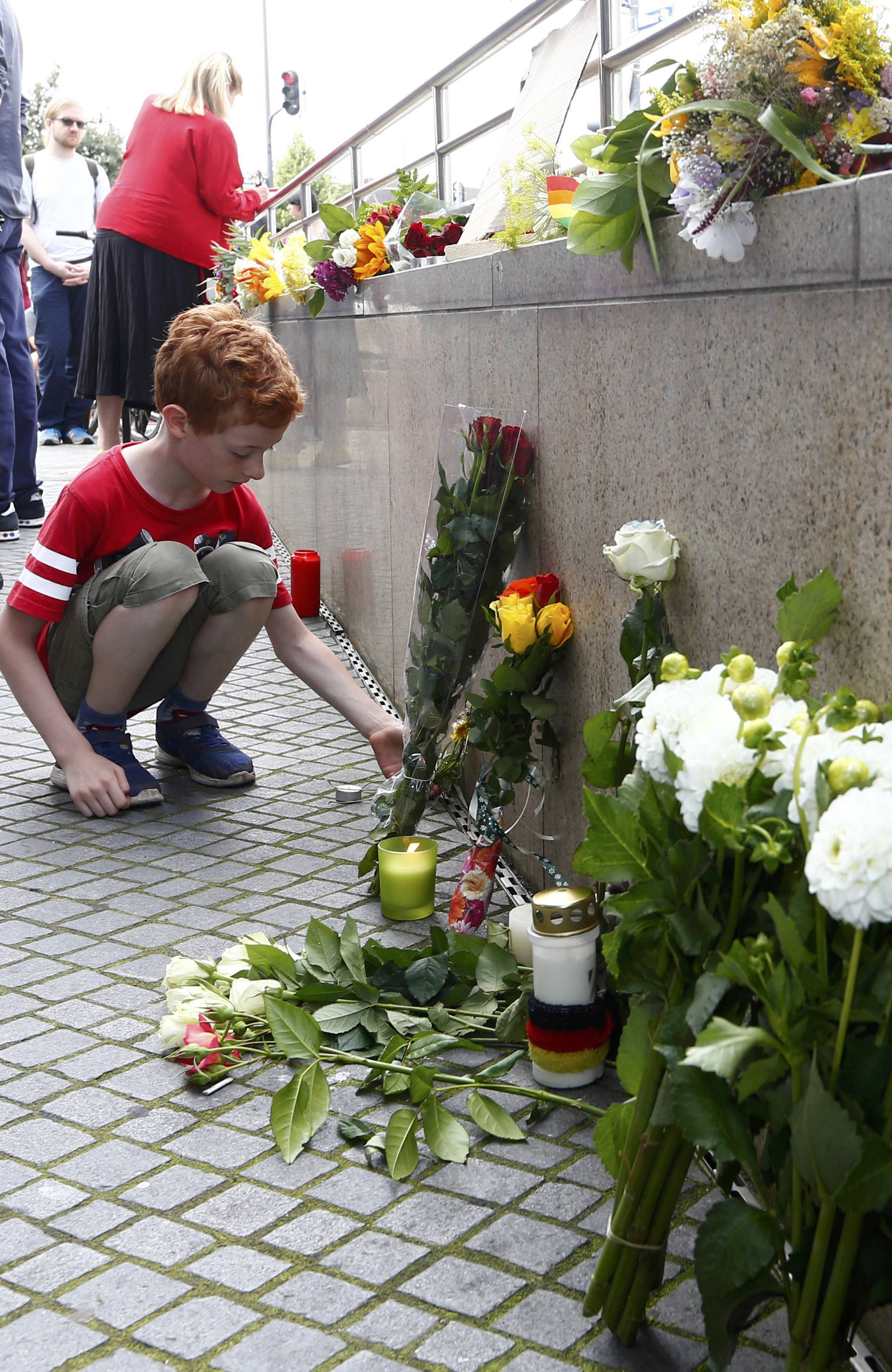 A young boy places flowers near Olympia shopping mall in Munich