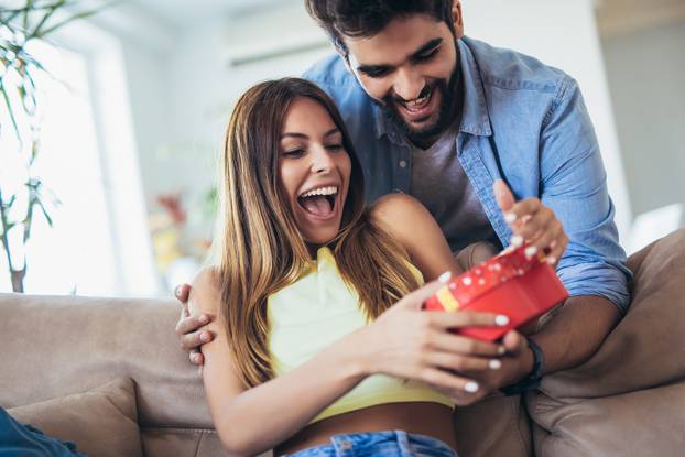 Man giving a surprise gift to woman at home