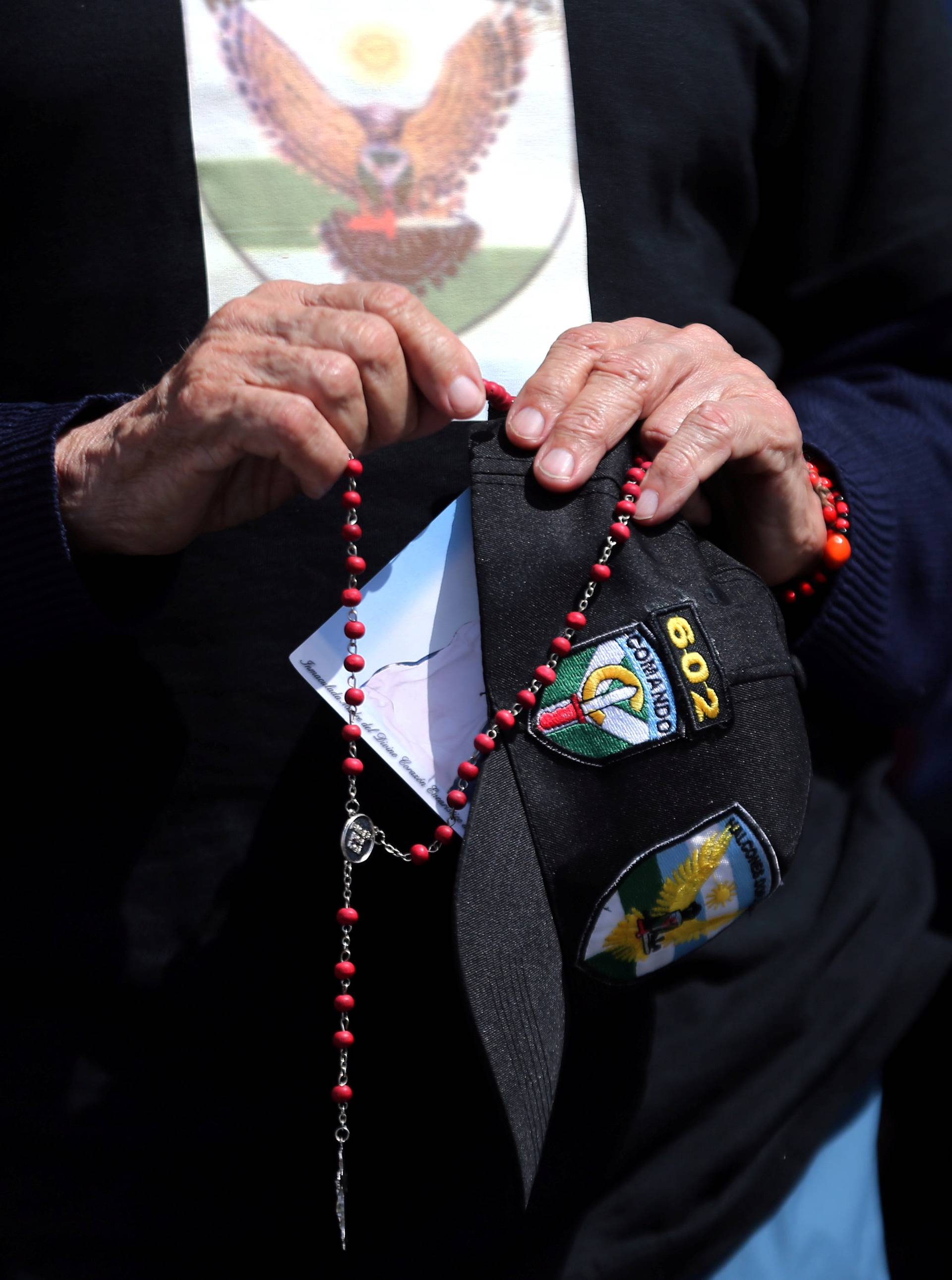 A man holds a rosary as he prays for the 44 crew members of the missing at sea ARA San Juan submarine, at the entrance of an Argentine Naval Base in Mar del Plata