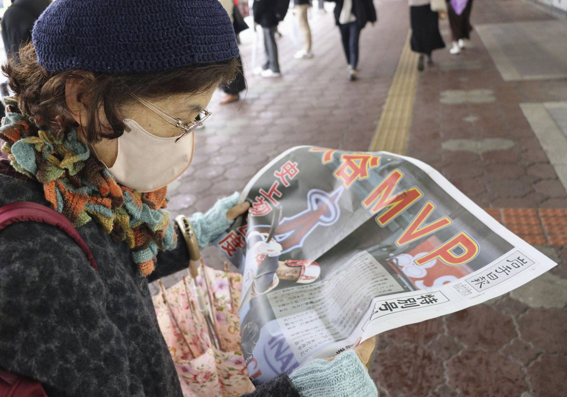 A woman reads a special edition about Shohei Ohtani’s winning his second American League MVP award, which is published by a local newspaper, at a railway station in Morioka