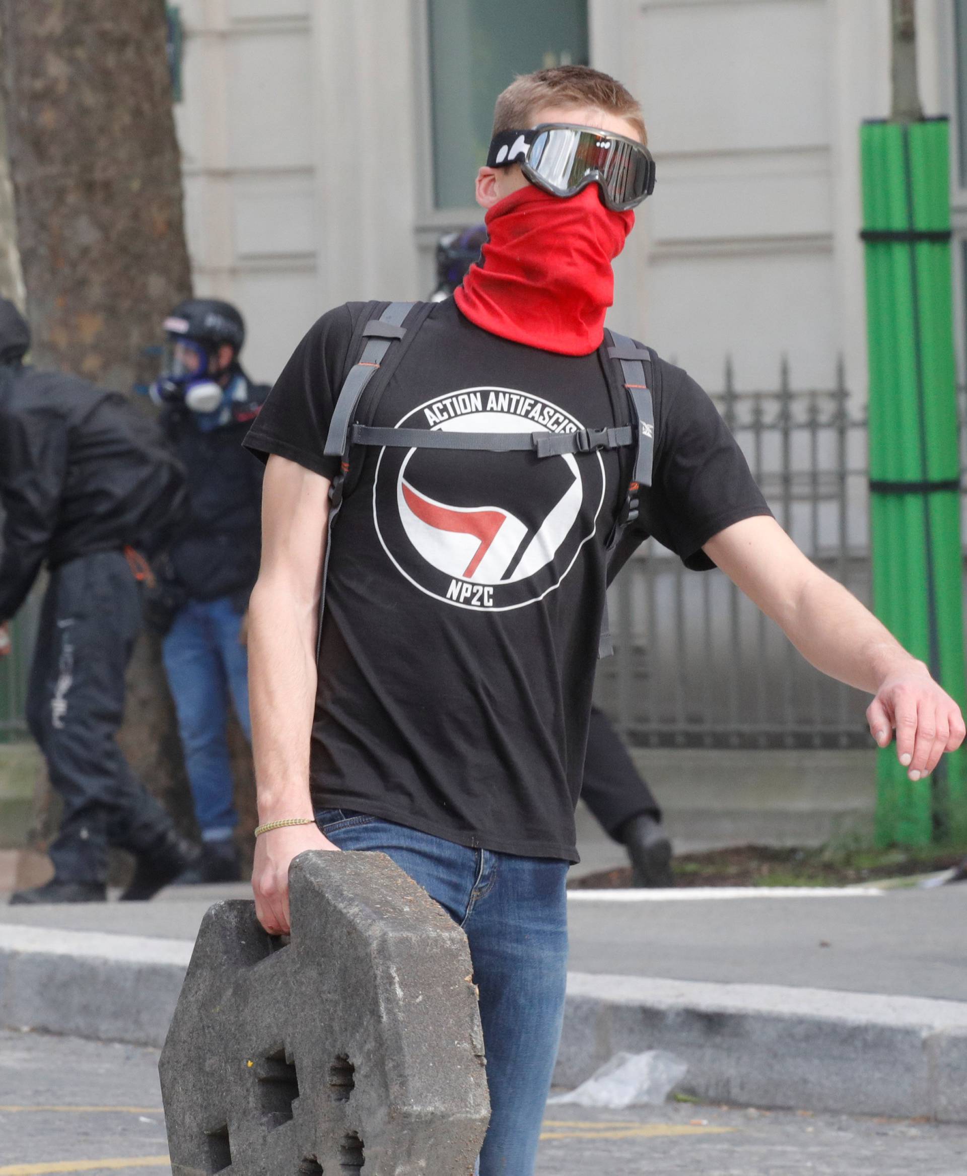 A demonstrator carries a piece of barrier, as he wears a t-shirt reading: "antifascist action", during clashes with French CRS riot police at the May Day labour union rally in Paris