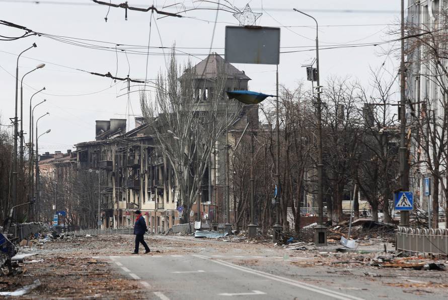 A local resident crosses a damaged street in Mariupol
