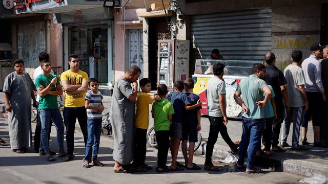 Palestinians wait to buy bread outside a bakery in Khan Younis