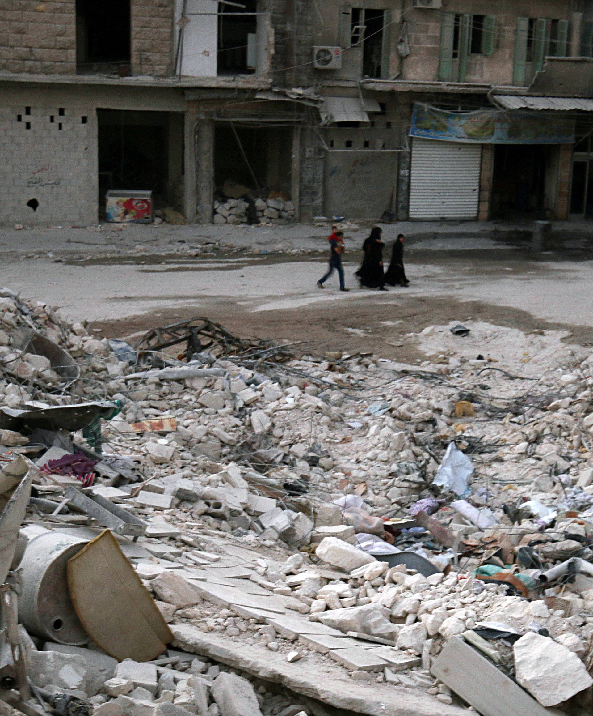 People walk past damaged buildings in the rebel held area of al-Kalaseh neighbourhood of Aleppo