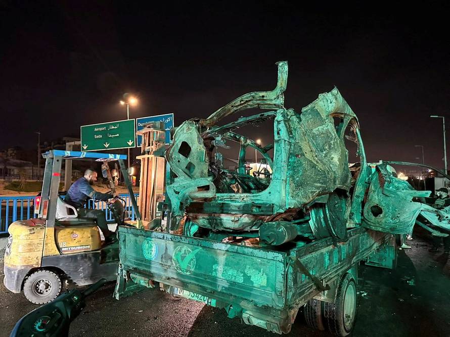 A truck carries a burned-out car that was hit by an Israeli airstrike in Beirut