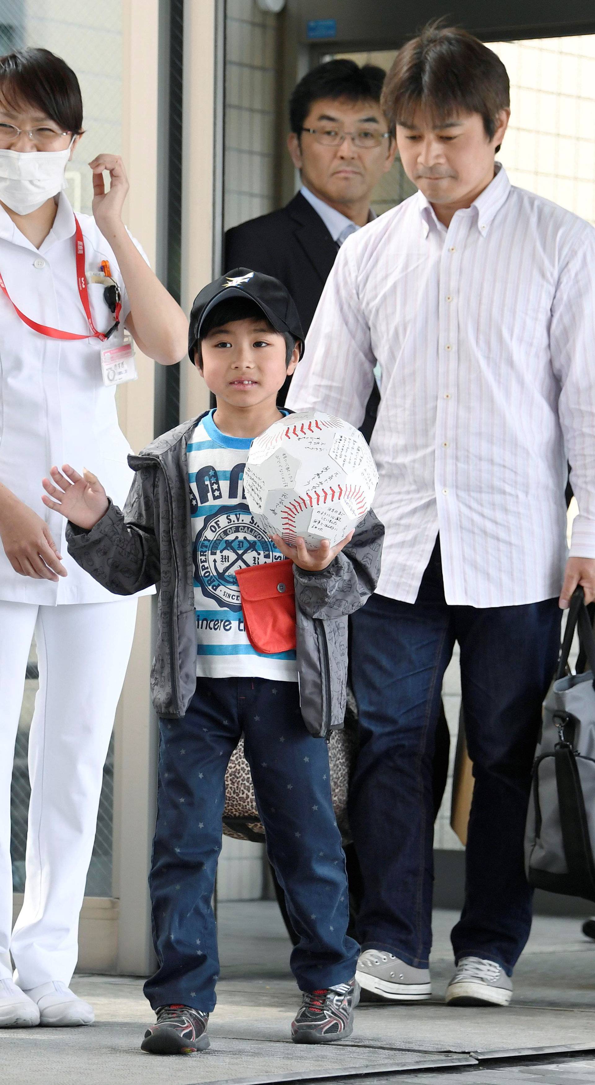 Yamato Tanooka, who was found by authorities in the woods nearly a week after his parents abandoned him for disciplinary reasons, waves as he leaves a hospital with his father Takayuki in Hakodate