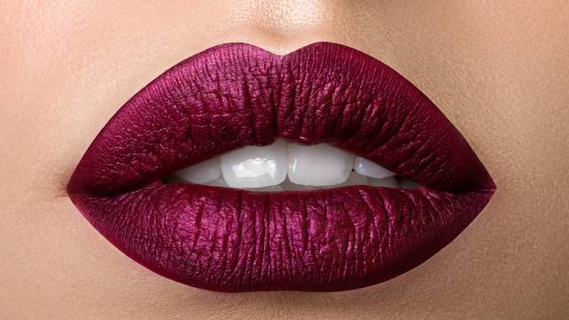 Close up view of beautiful woman lips with purple matt lipstick