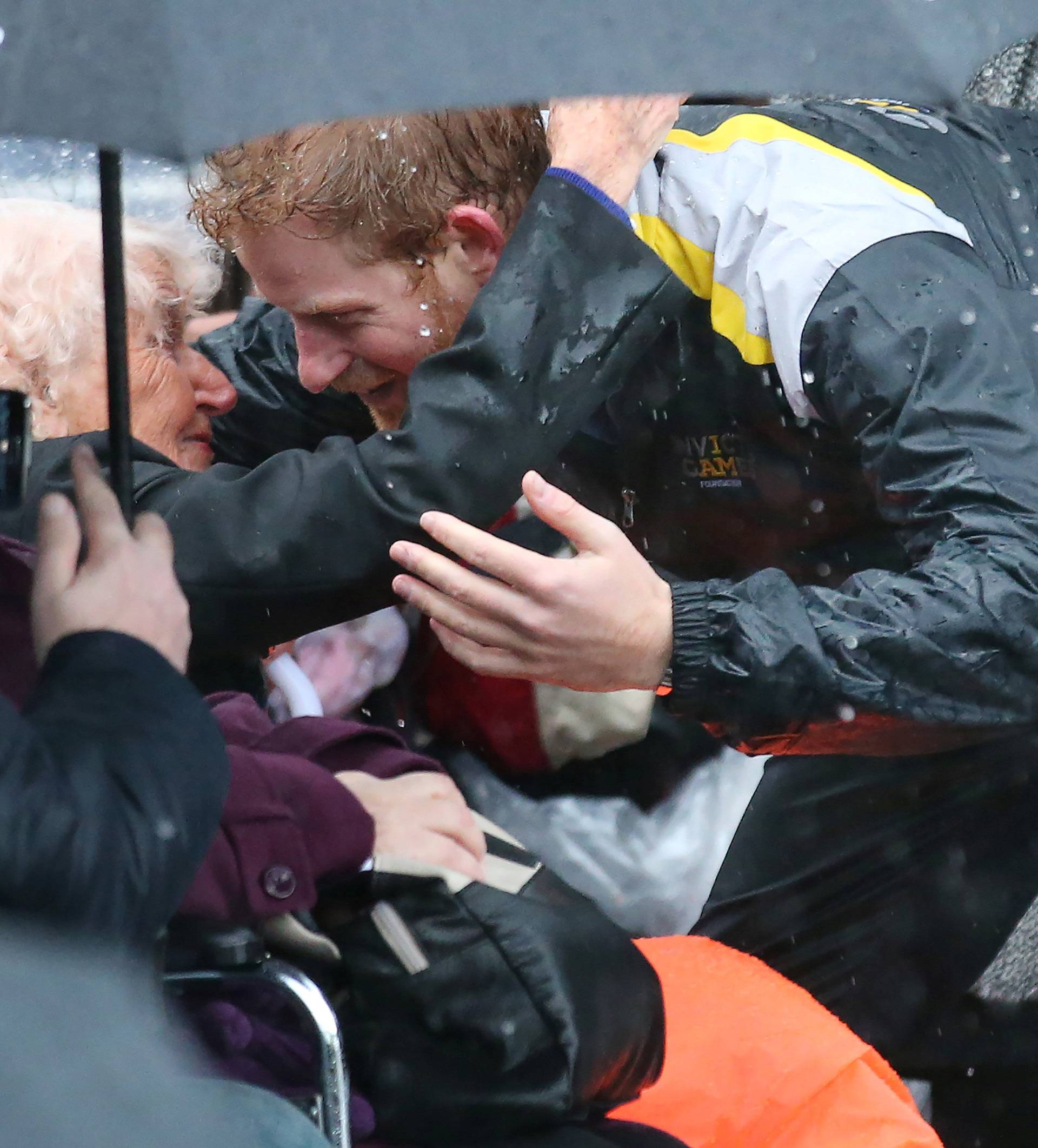 Britain's Prince Harry hugs Daphne Dunne, 97, during a walk around The Rocks district in rainy Sydney