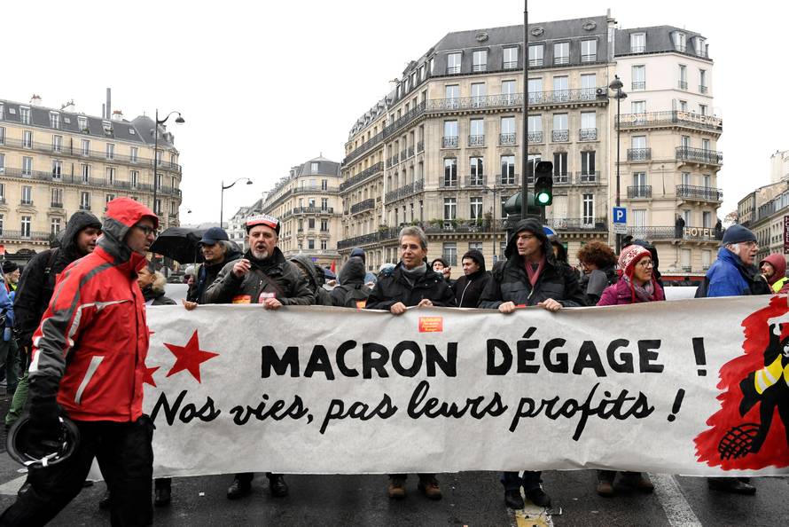 People hold a banner which reads "Macron get out, our lives, not our profits" as they demonstrate in a street during a national day of protest by the "yellow vests" movement in Paris