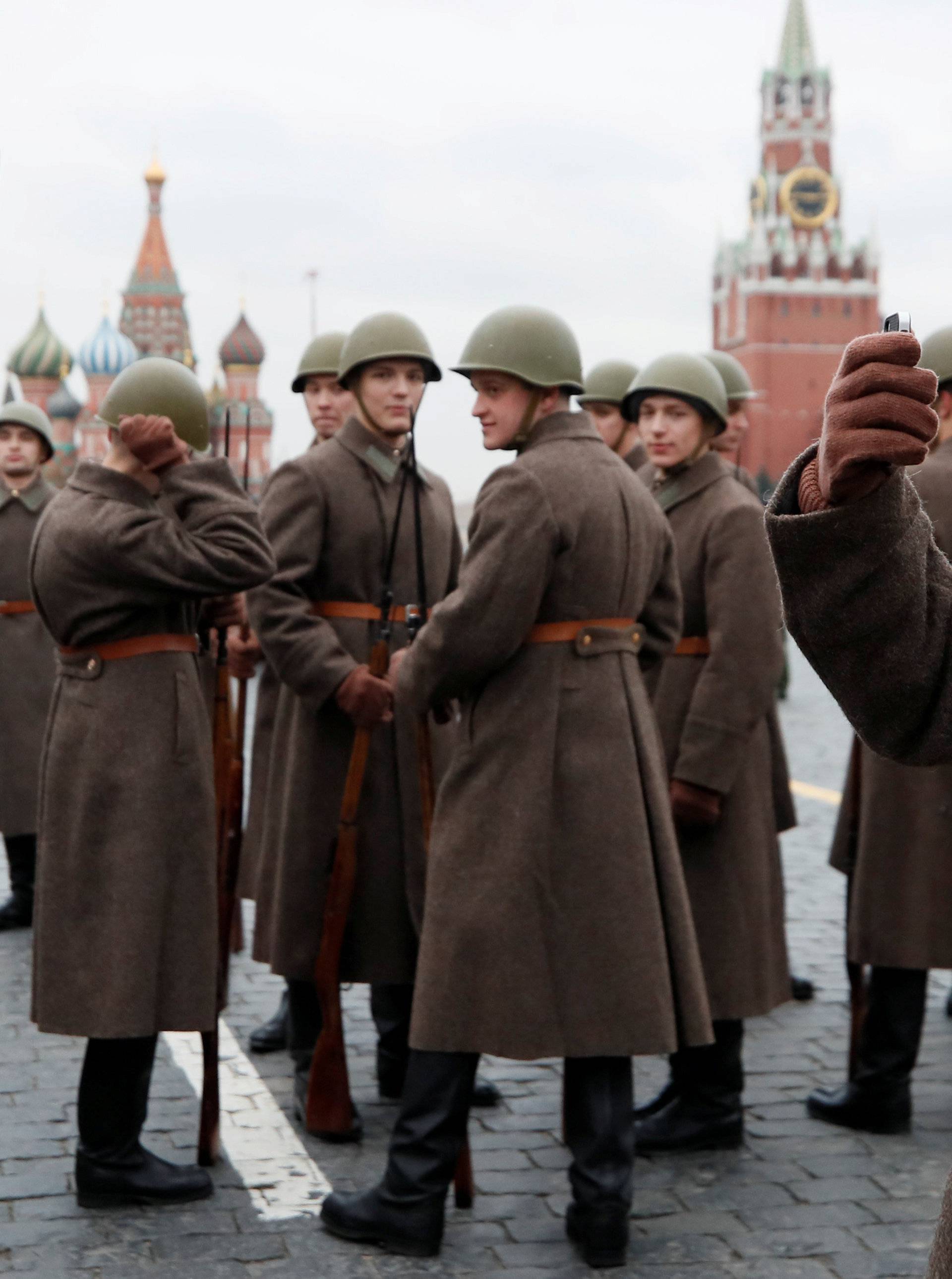 A Russian serviceman dressed in historical uniform uses his mobile device as he waits before a military parade marking the anniversary of the 1941 parade, when Soviet soldiers marched towards the front lines of World War Two, in Red Square in Moscow