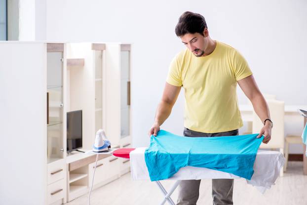 The handsome man husband doing clothing ironing at home