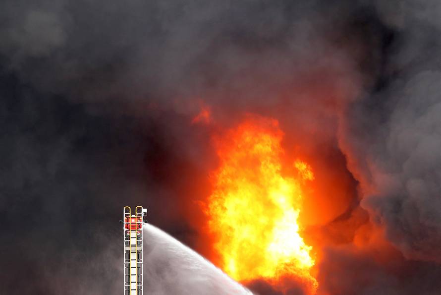 Fire crews operate a hose attached to a ladder at a fire in a factory in Melbourne