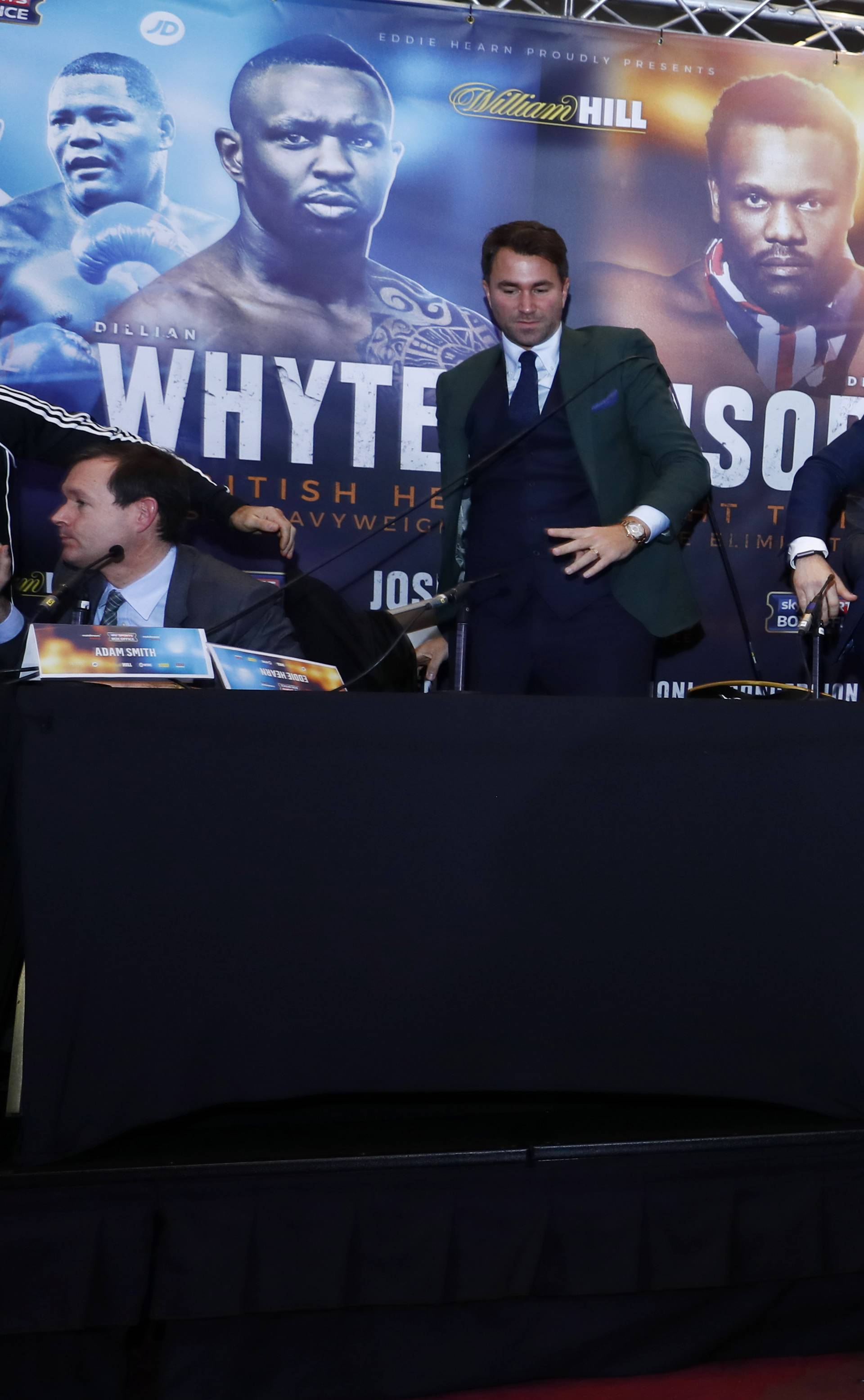 Sky Sports' Adam Smith, promoter Eddie Hearn and promoter Kalle Sauerland look on as Dereck Chisora throws a table towards Dillian Whyte during the press conference