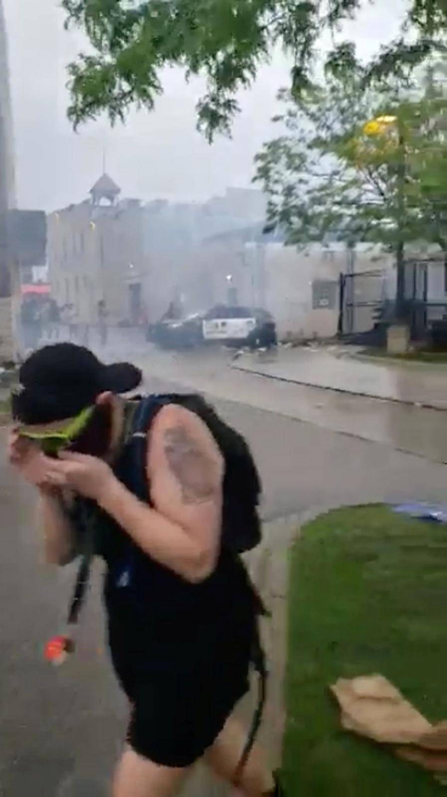 A protester wearing a face mask runs from tear gas fired by police during a protest after the death of George Floyd in Minneapolis