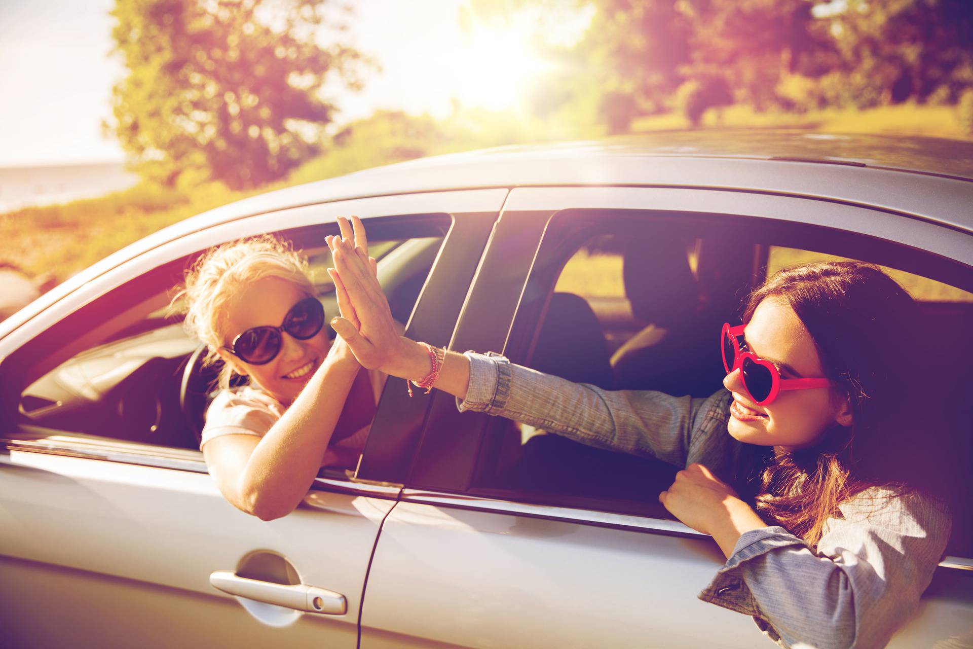 happy teenage girls or women in car at seaside