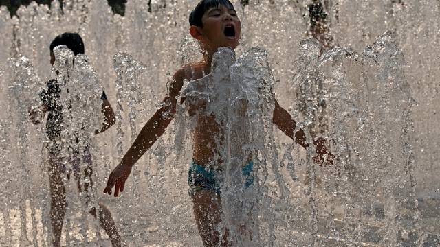 Children cool off from hot weather in a fountain in Shanghai