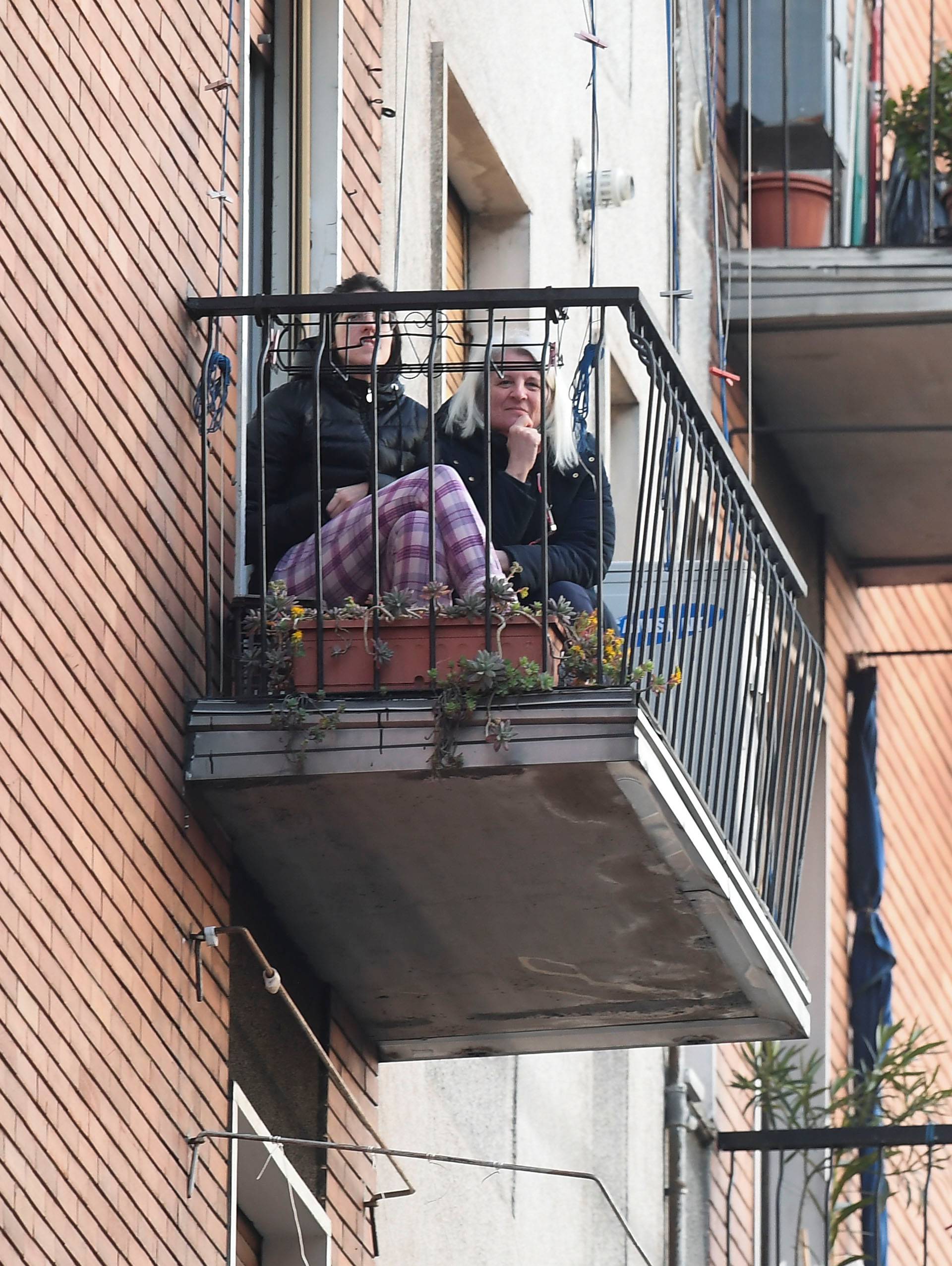 Woman listen to music as a neighbor plays the guitar from a balcony to raise morale on the sixth day of an unprecedented lockdown across of all Italy imposed to slow the outbreak of coronavirus in Milan