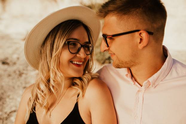 man and woman in hat are sitting on large stone rock