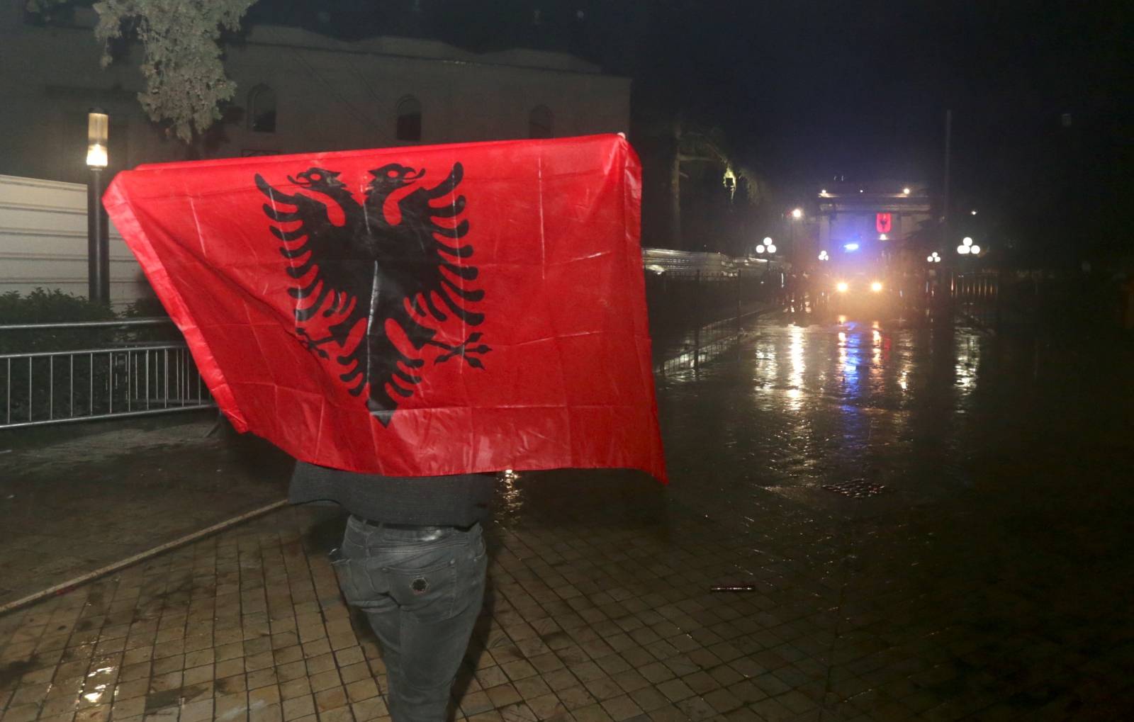 A supporter of the opposition party carries an Albanian flag as he attends an anti-government protest in front of the Parliament Building in Tirana