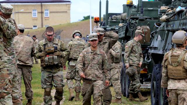 U.S. soldiers walk past Stryker armoured fighting vehicles in Suwalki