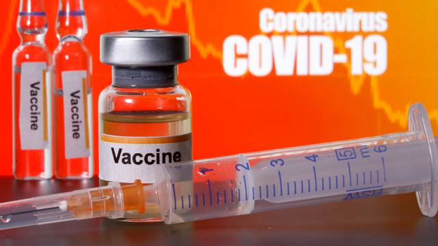 FILE PHOTO: Small bottles labeled with "Vaccine" stickers stand near a medical syringe in front of displayed "Coronavirus COVID-19" words in this illustration