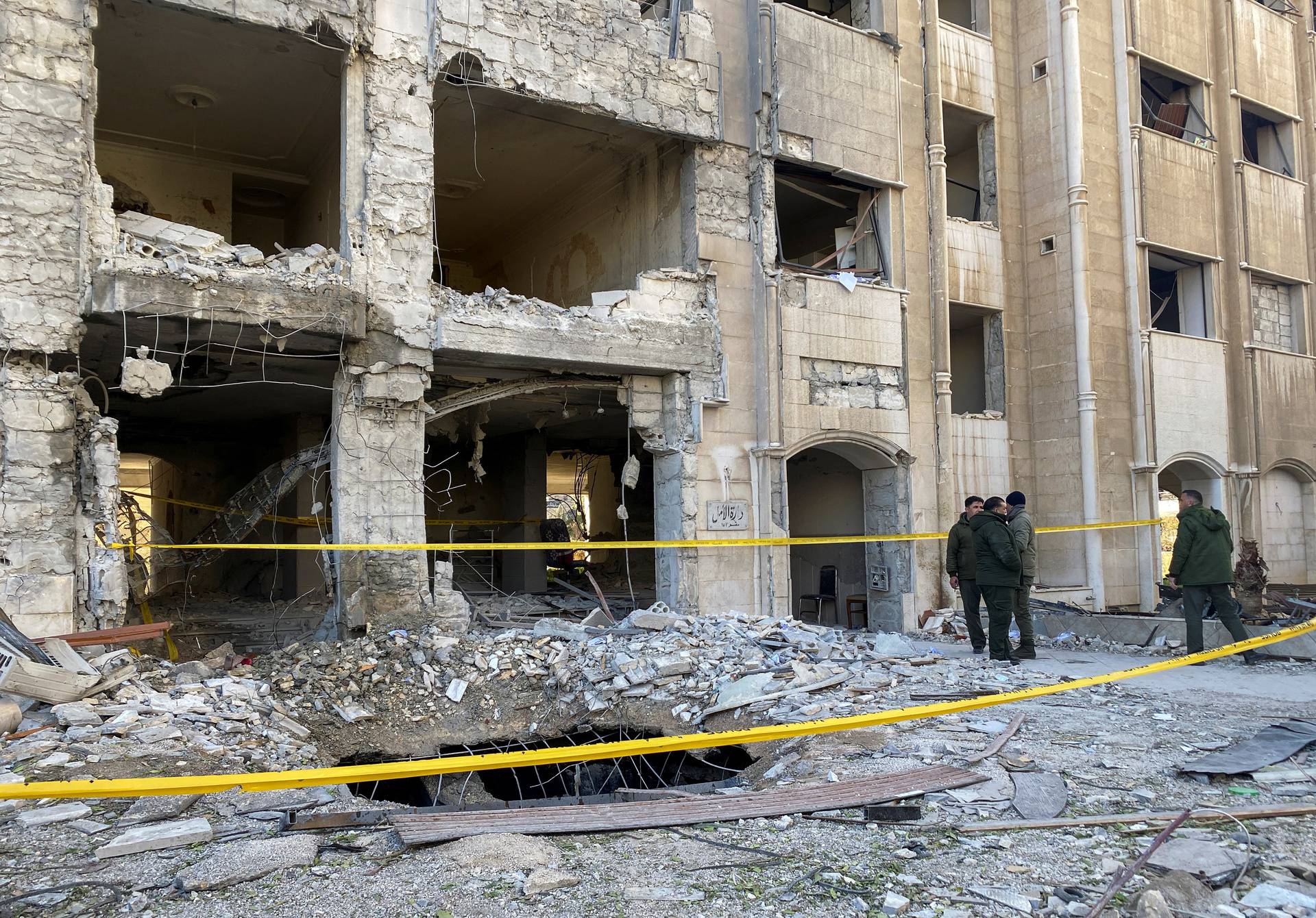 Police members stand at the site of a rocket attack, in central Damascus' Kafr Sousa neighborhood