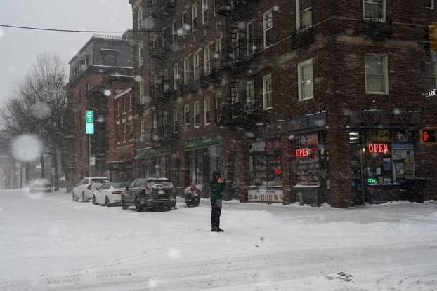 FILE PHOTO: A pedestrian uses his mobile phone to photograph snowfall, in Brooklyn