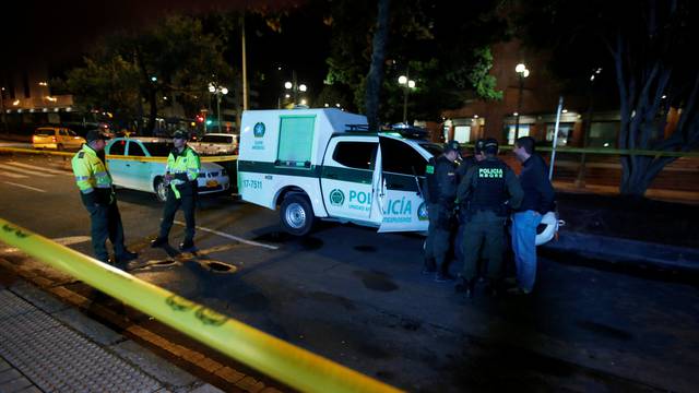 Police officers stand behind a yellow tape outside the Andino shopping center after an explosive device detonated in a restroom, in Bogota