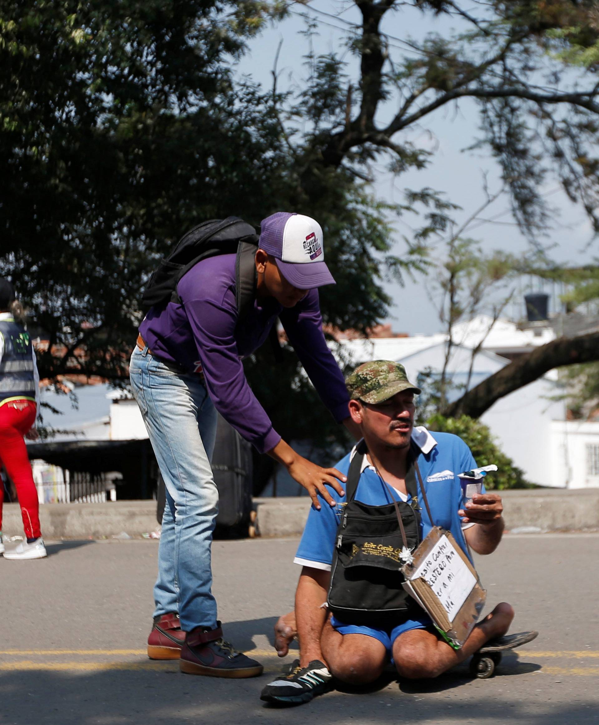 A man helps to push the skateboard of a man with with mobility issues at the Francisco de Paula Santander international bridge in Cucuta