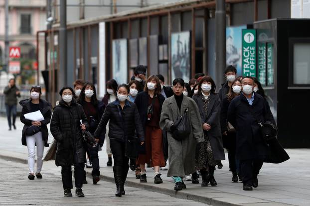 Tourists wearing protective masks walk near Duomo square, as a coronavirus outbreak continues to grow in northern Italy, in Milan
