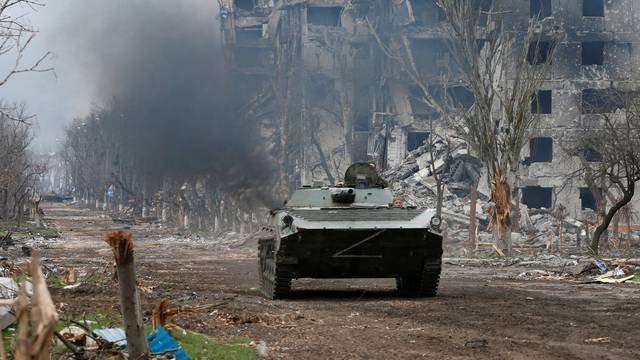 Service members of pro-Russian troops ride an armoured vehicle during fighting near Azovstal plant in Mariupol