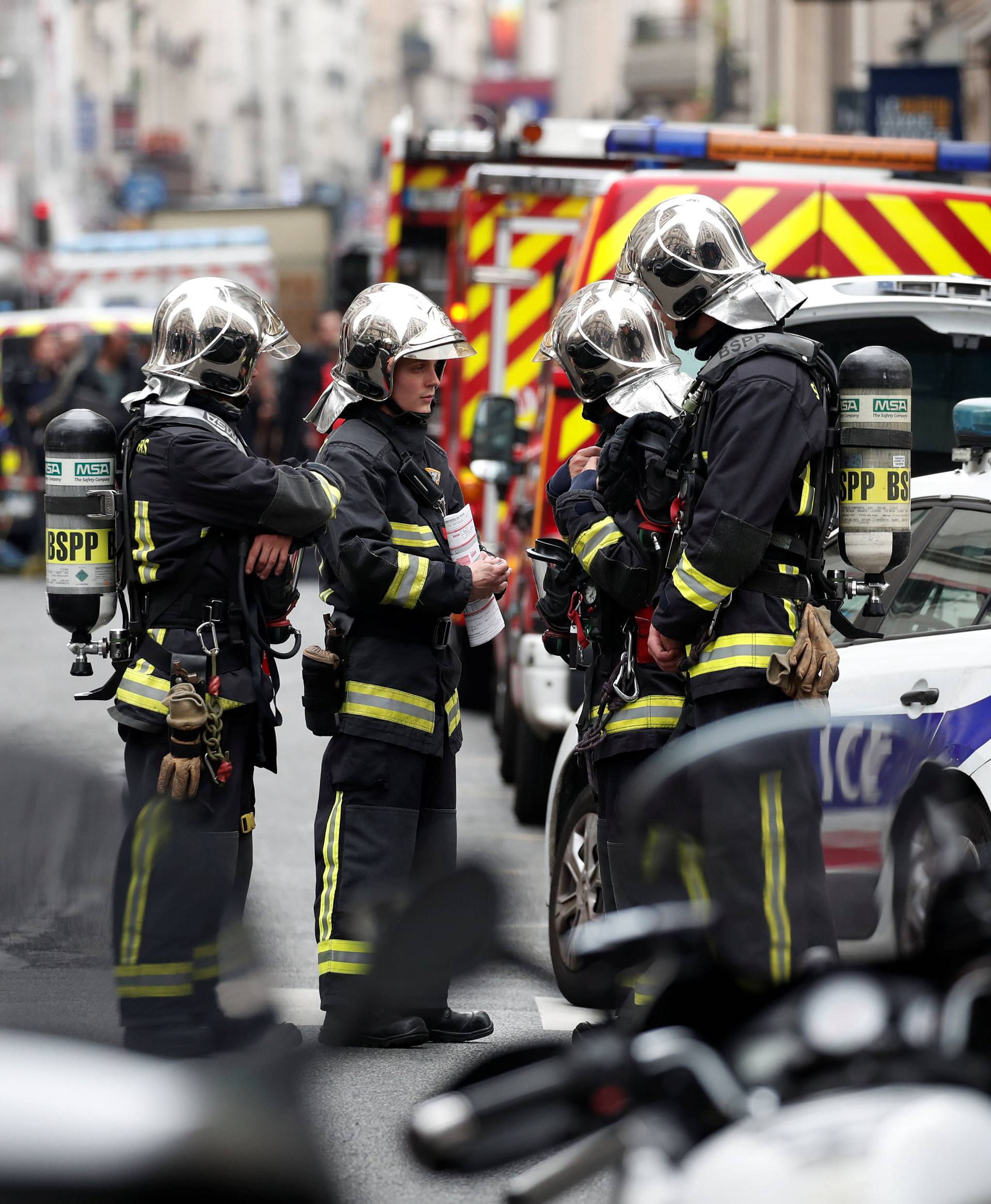 French police and firemen secure the street as a man has taken people hostage at a business in Paris