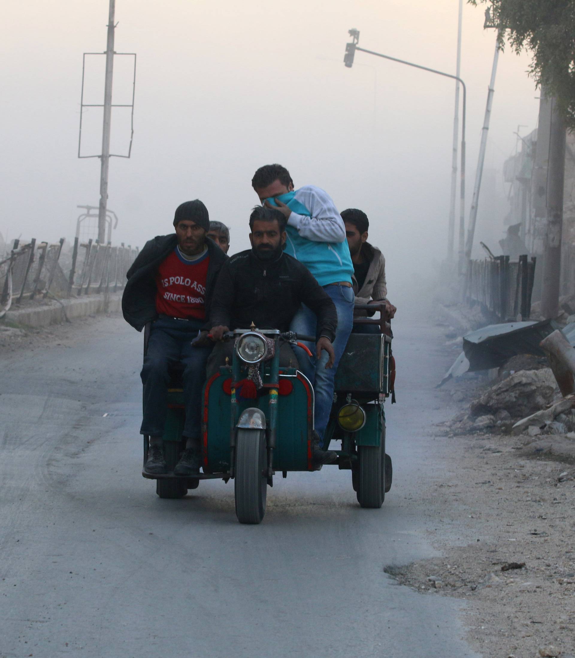 Men ride on a vehicle amidst dust after a strike on the rebel held besieged al-Shaar neighbourhood of Aleppo, Syria