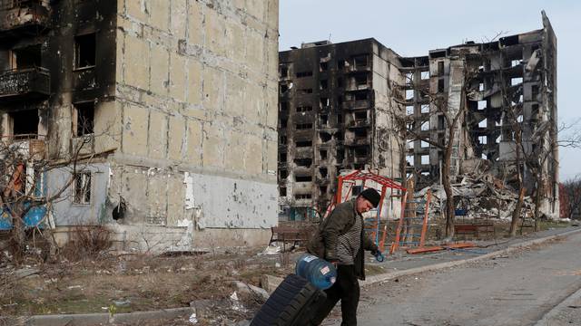 A local resident walks past destroyed apartment buildings in Mariupol